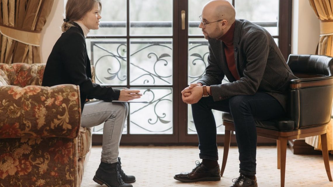 A thought-provoking therapy session with therapist and client discussing in a cozy room.